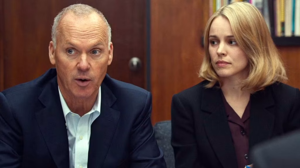 Michael Keaton and Rachel McAdams sitting together in a Spotlight newsroom scene.