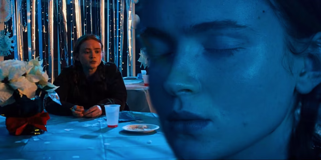 Max sits alone at a table during the Snow Ball in Stranger Things.