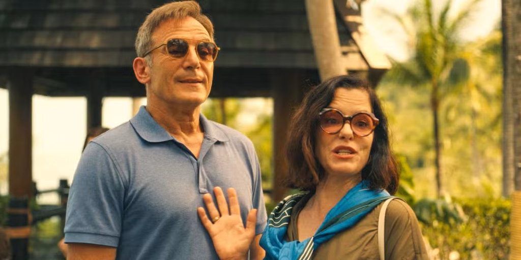 Timothy and Victoria Ratliff stand outdoors at the resort wearing sunglasses, with Victoria raising one hand as they look ahead.