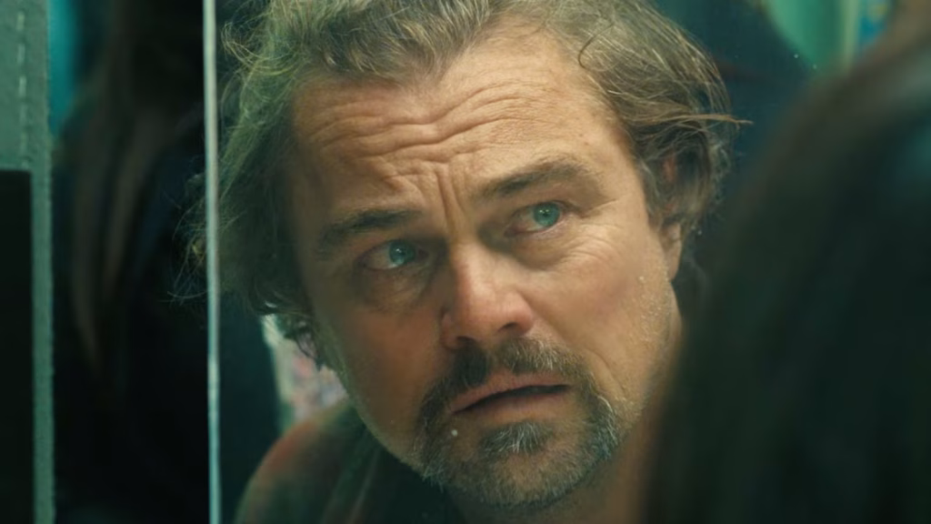Close-up of a distressed man with watery eyes looking off to the side behind a glass surface.