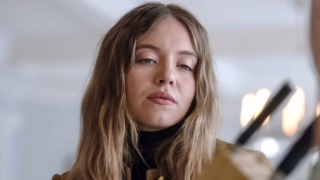 Close-up of Sydney Sweeney’s character looking wary, with a blurred kitchen utensil in the foreground.