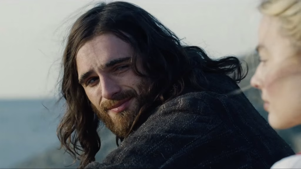 Jacob Elordi as Heathcliff looks toward Catherine in a close outdoor scene from the Wuthering Heights (2026) trailer.
