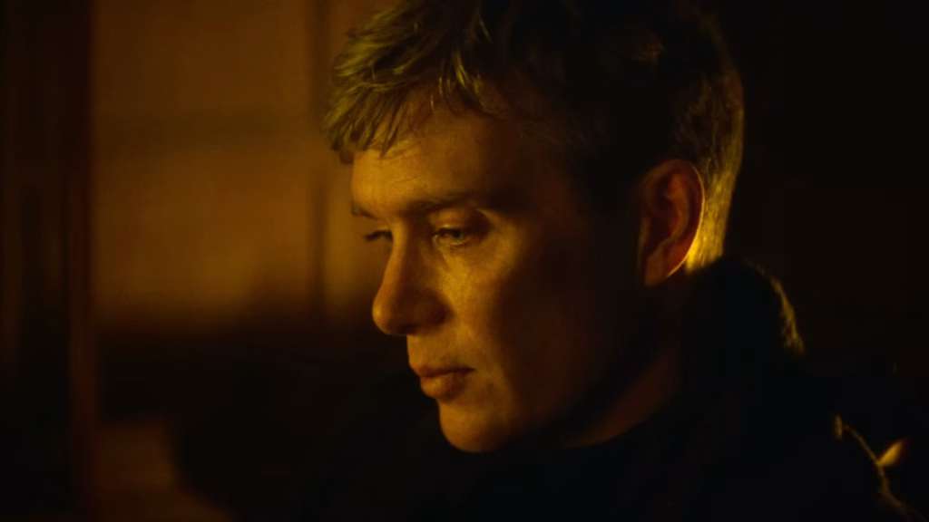 Close-up of Tommy Shelby in warm low light, looking down with a serious expression in Peaky Blinders: The Immortal Man.