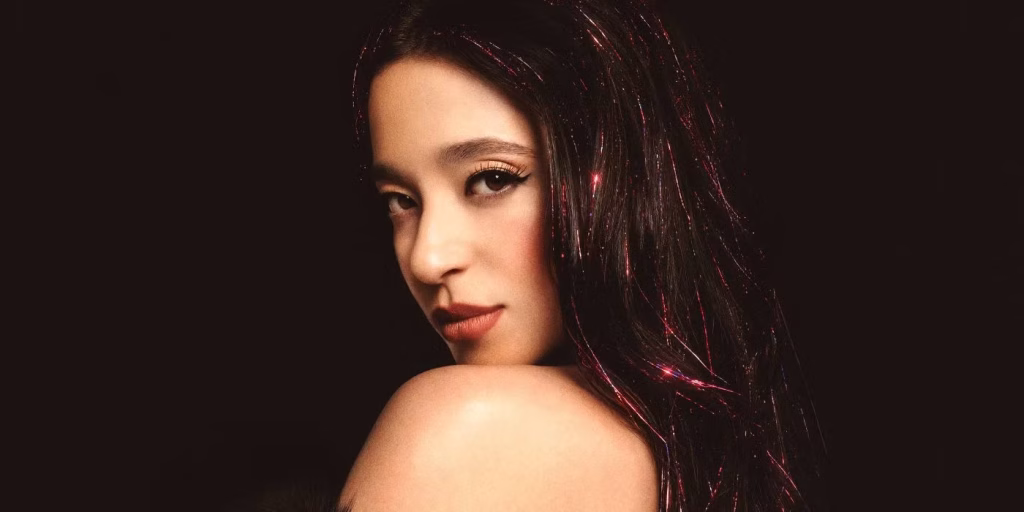 Official Anora movie poster showing Mikey Madison as Ani against a New York backdrop with the film title in bold pink lettering.