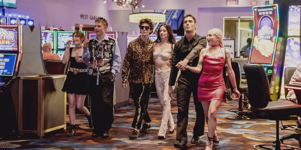 Ani walks through a casino with a small group in Anora, surrounded by bright slot machines and nightlife-style lighting.