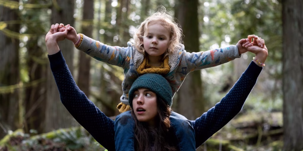 Alex carries Maddy on her shoulders in a forest scene from Maid.