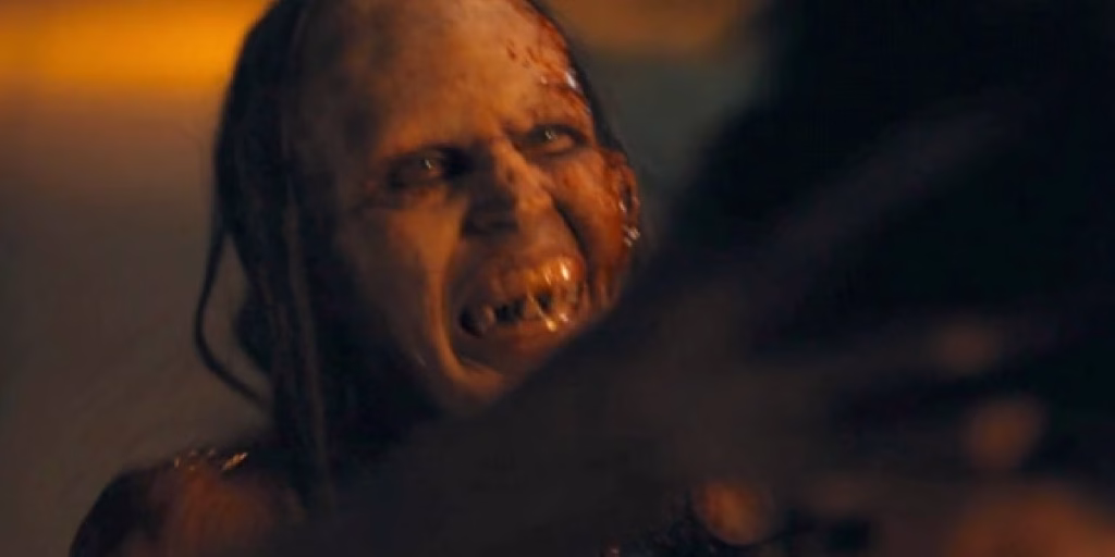 The Mother snarls at someone in a dark, orange-lit scene from Barbarian.