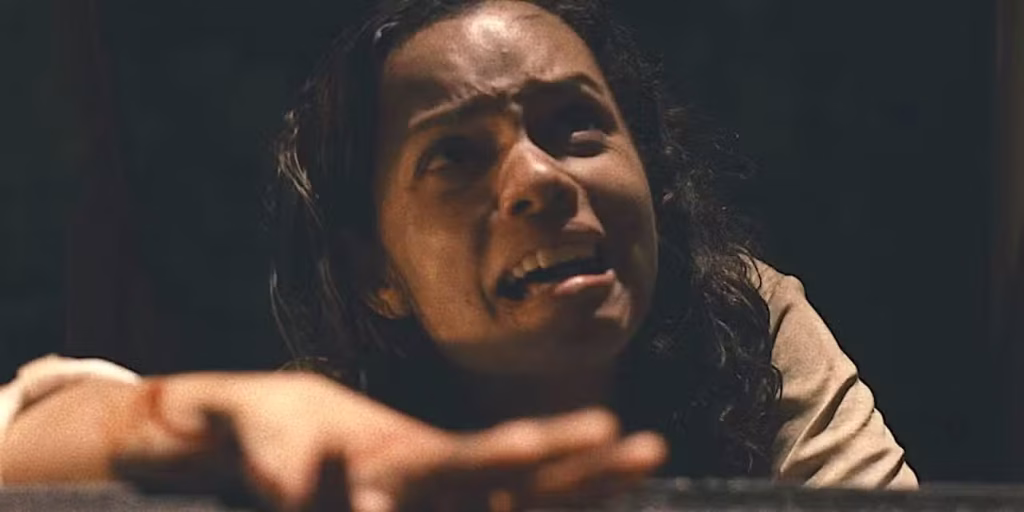 Tess from Barbarian reaches forward in terror during a dark, intense scene.