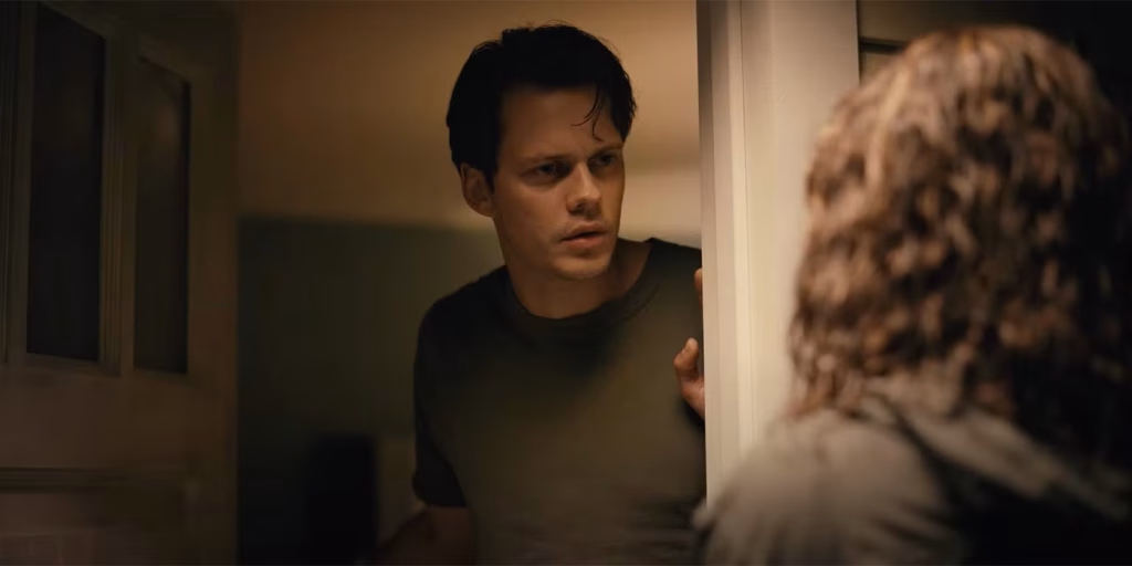 Bill Skarsgård as Keith looks through a doorway at Tess in Barbarian.