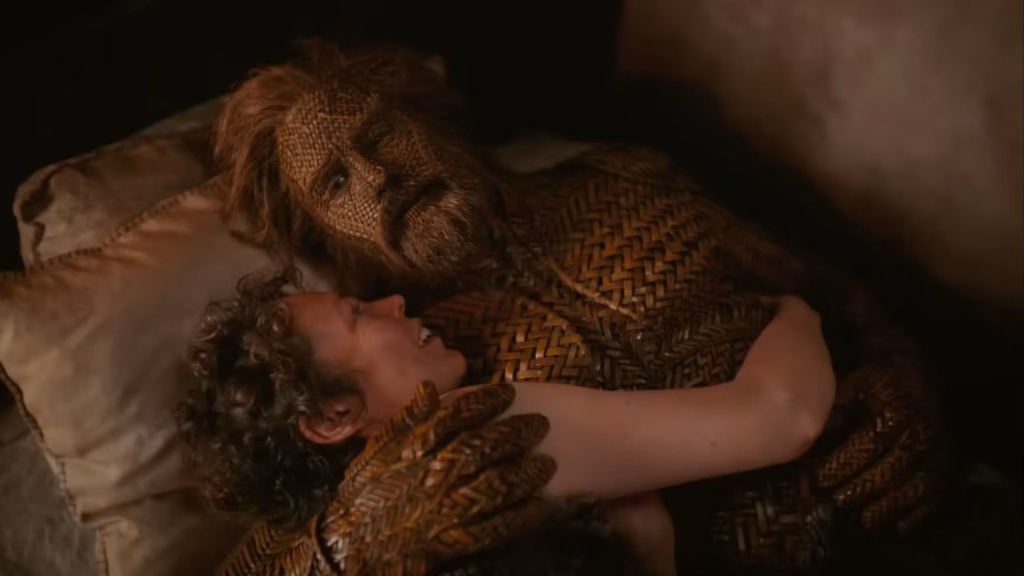 Olivia Colman embraces Alexander Skarsgård’s Wicker Husband while lying in bed.